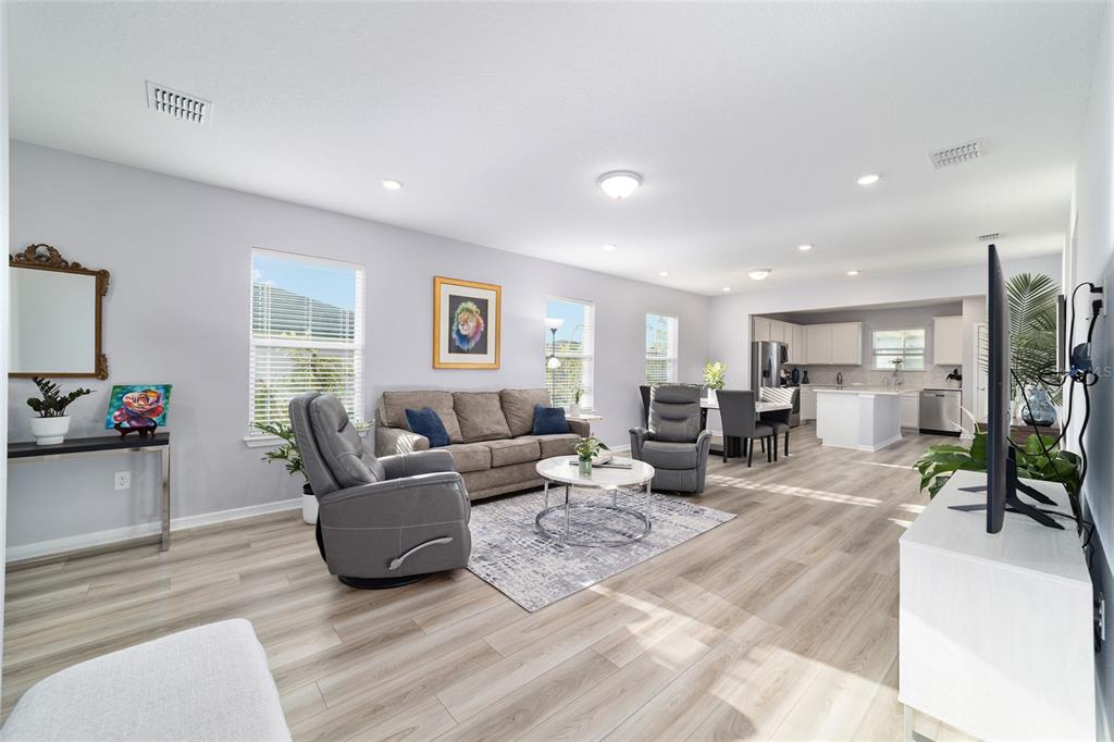 An open-concept living room and kitchen feature light wood-look flooring and neutral gray walls — 5472 SW 85TH AVENUE ROAD, OCALA, FL