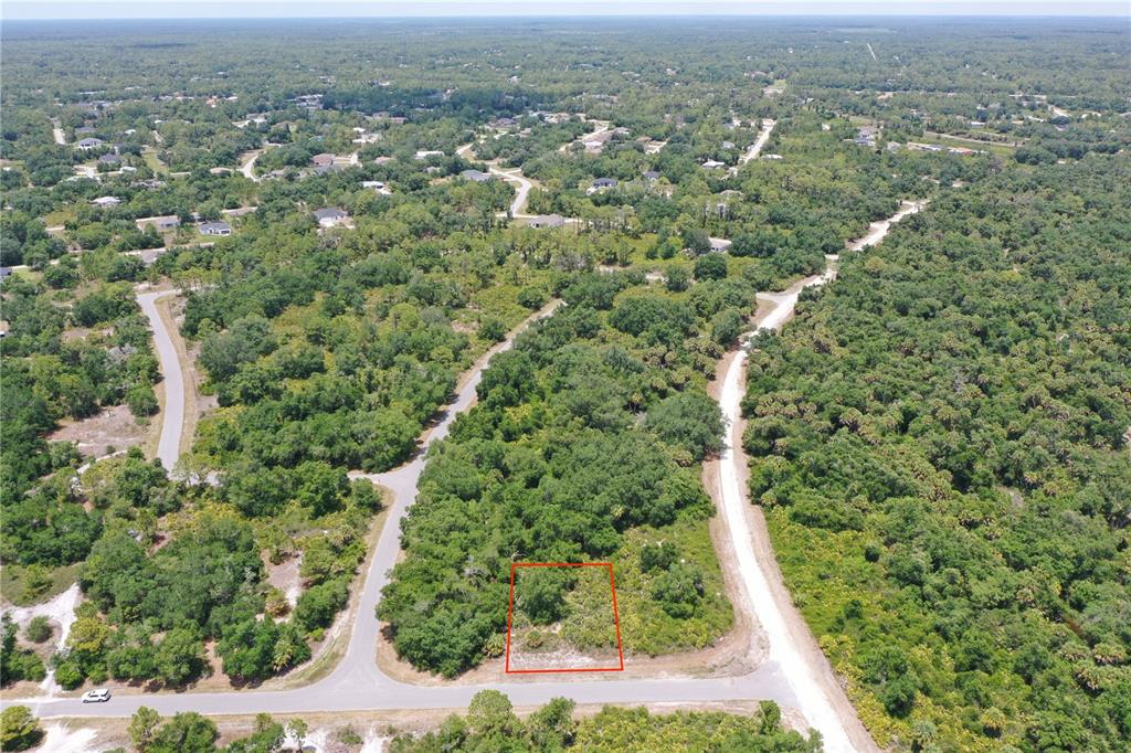 An aerial view shows a vacant, wooded residential lot outlined in red along a paved road — Lot 10 BRIXTON TERRACE, NORTH PORT, FL
