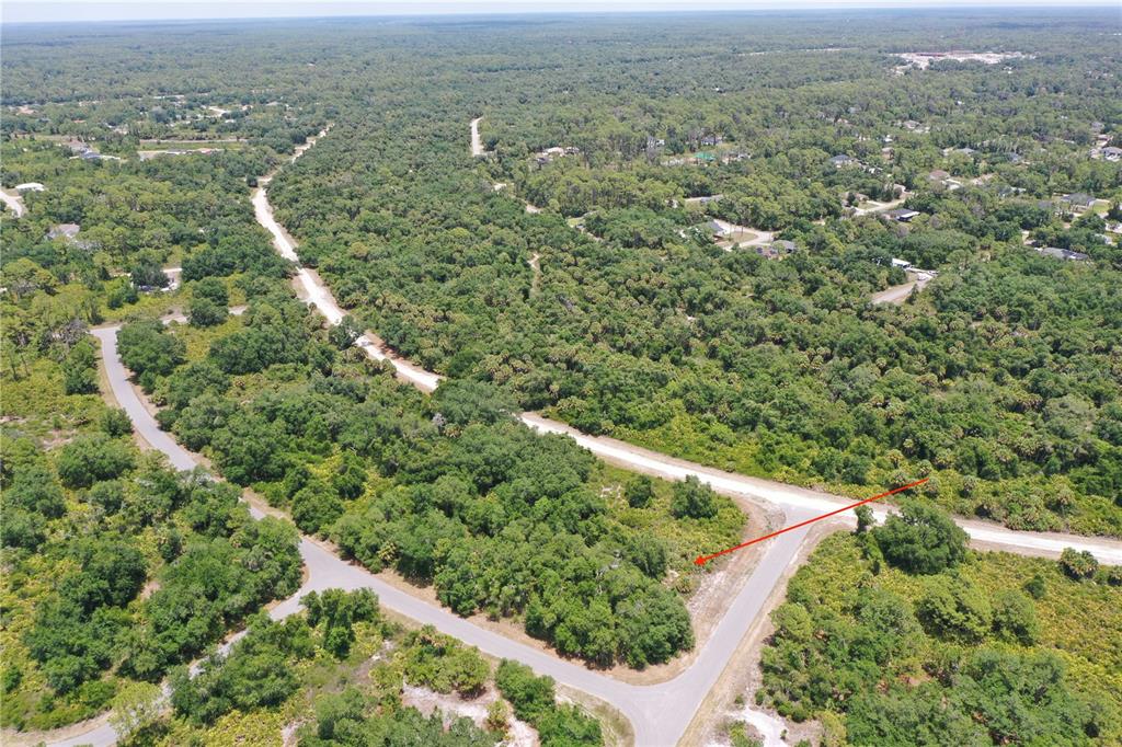 An aerial view shows a vacant, wooded residential lot at a paved road intersection — Lot 10 BRIXTON TERRACE, NORTH PORT, FL