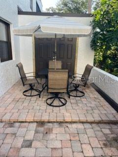 A patio with a table, four chairs, and a striped umbrella sits against a building wall — 5056 MARSH FIELD ROAD UNIT 7, SARASOTA, FL