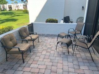 A paved patio features several outdoor chairs and a footstool against a low white wall — 5056 MARSH FIELD ROAD UNIT 7, SARASOTA, FL