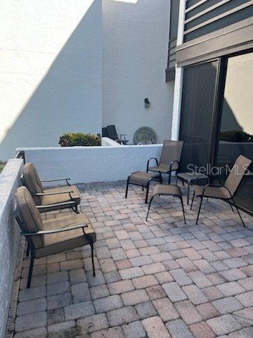 A paved patio features several outdoor chairs and a low wall against a building exterior — 5056 MARSH FIELD ROAD UNIT 7, SARASOTA, FL