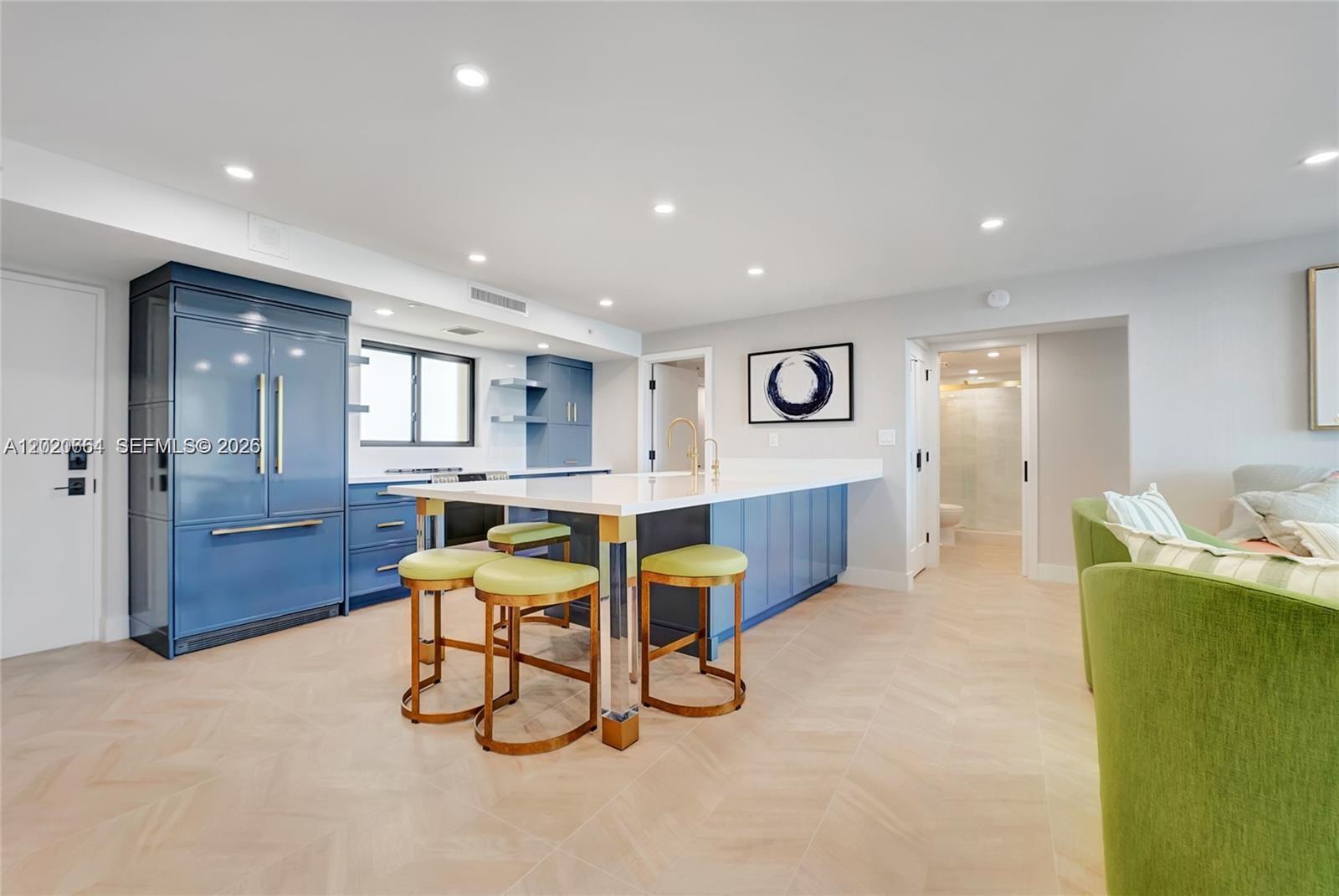 A modern kitchen features blue cabinetry, a white island with gold legs, and light flooring — 300 Ocean Trail Way # 702, Jupiter FL 33477, JUPITER, FL