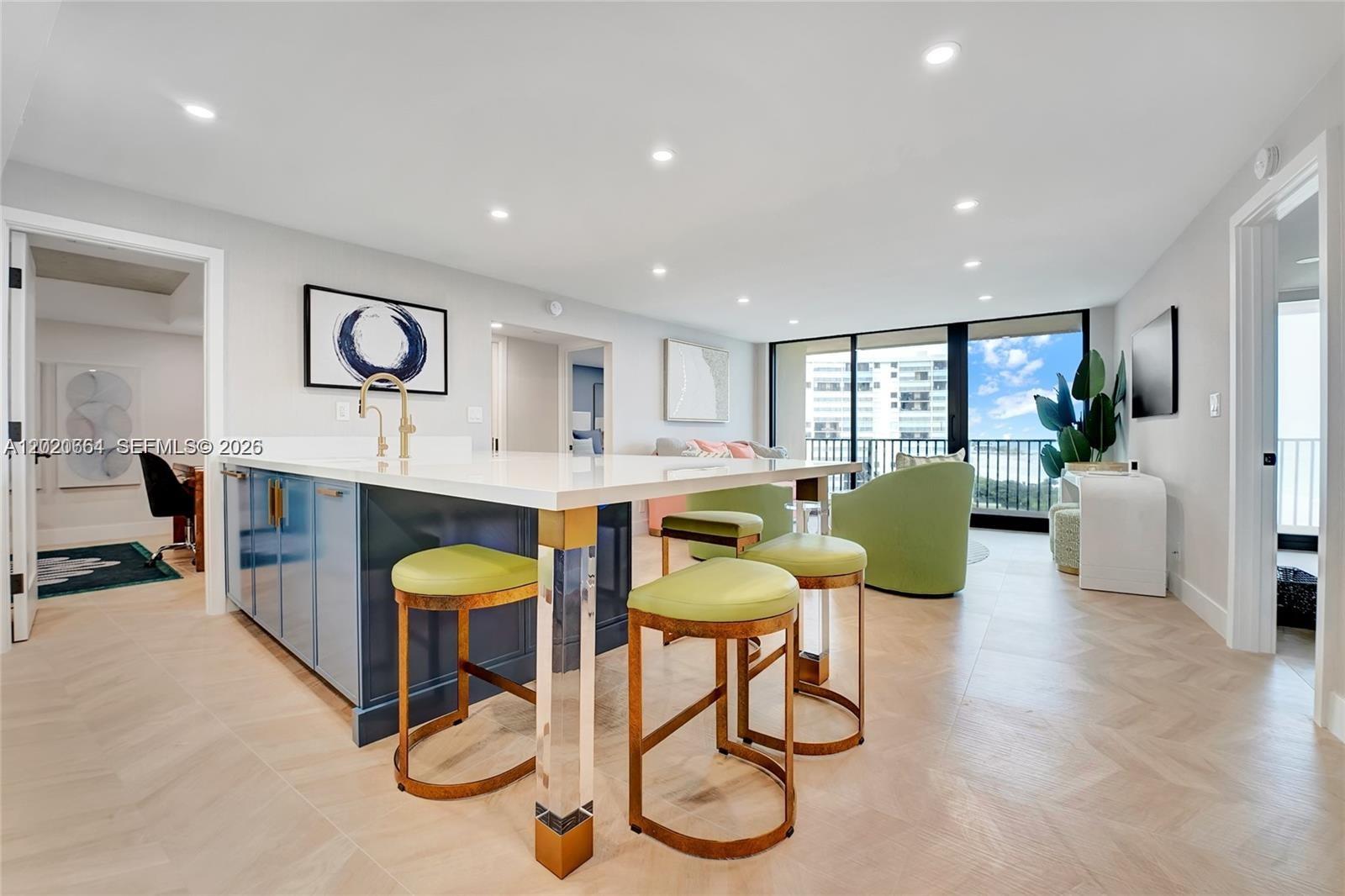 A kitchen island with blue cabinets and bar stools sits in a bright open-concept room — 300 Ocean Trail Way # 702, Jupiter FL 33477, JUPITER, FL
