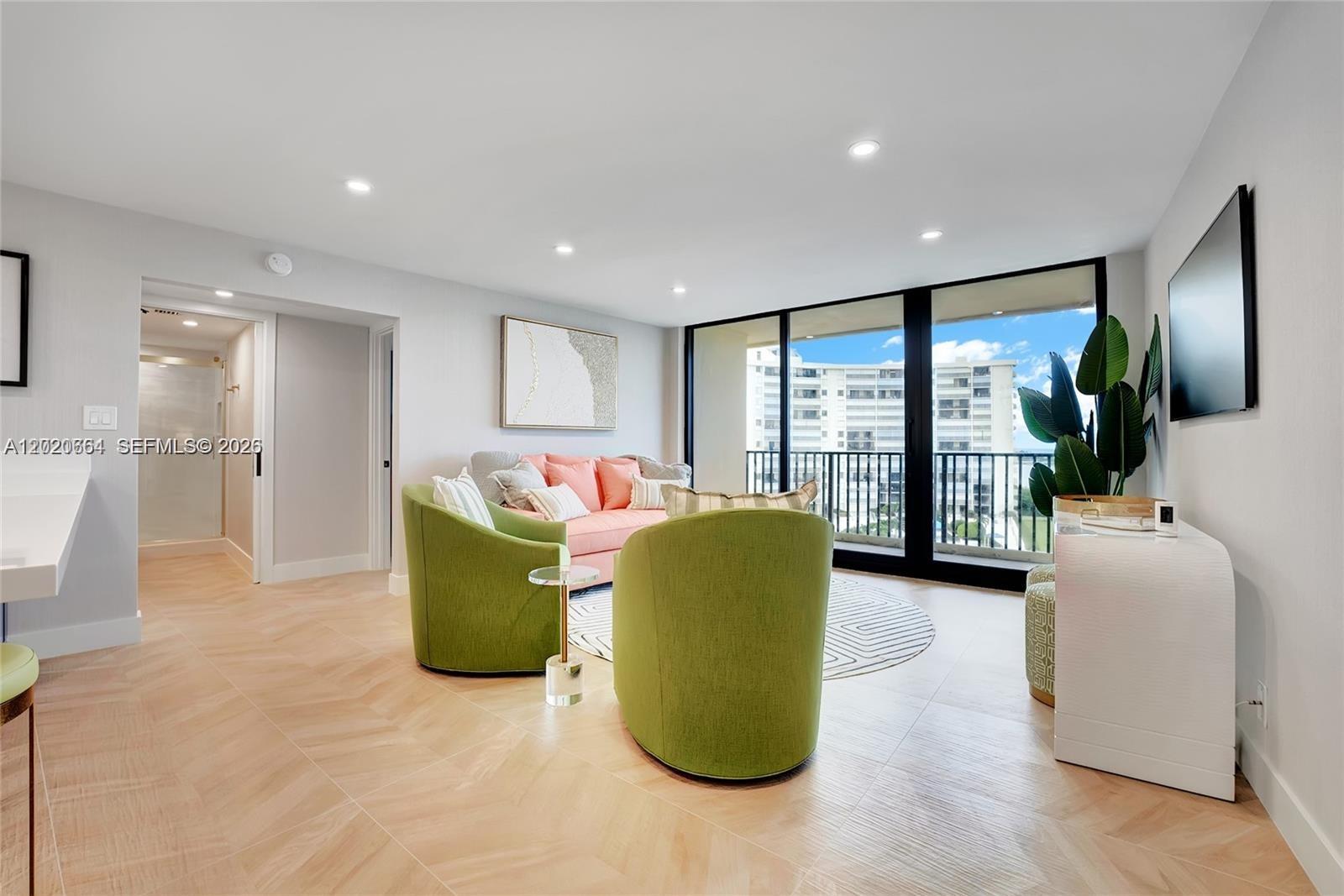 A living room features green armchairs, a pink sofa, light wood flooring, and a balcony — 300 Ocean Trail Way # 702, Jupiter FL 33477, JUPITER, FL