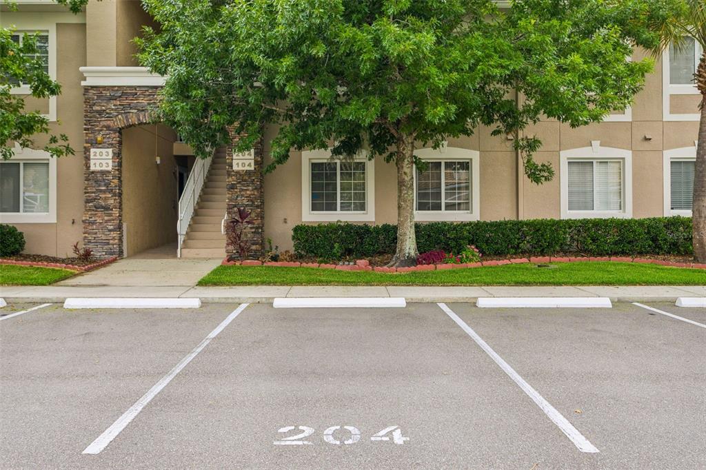 An exterior view of an apartment building with a parking space labeled 204 — 1231 GODAVARI WAY UNIT 204, WESLEY CHAPEL, FL