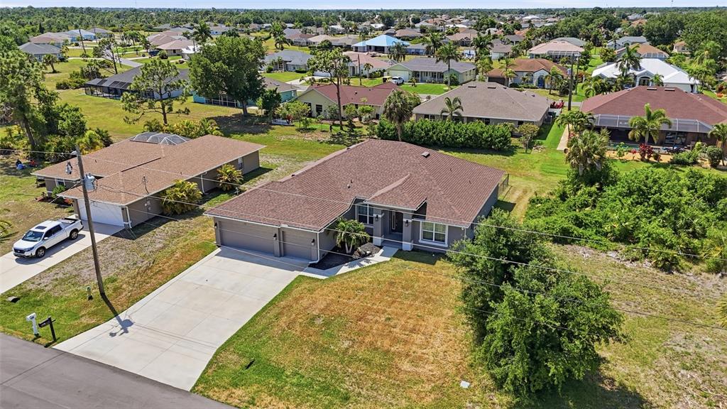 An aerial view shows a single-story house with a brown roof and concrete driveway — 119 LONG MEADOW LANE, ROTONDA WEST, FL