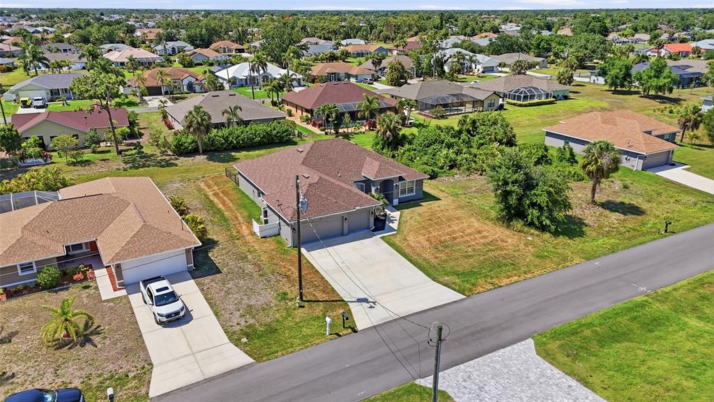 An aerial view shows a suburban neighborhood with single-family homes, paved driveways, and green lawns — 119 LONG MEADOW LANE, ROTONDA WEST, FL