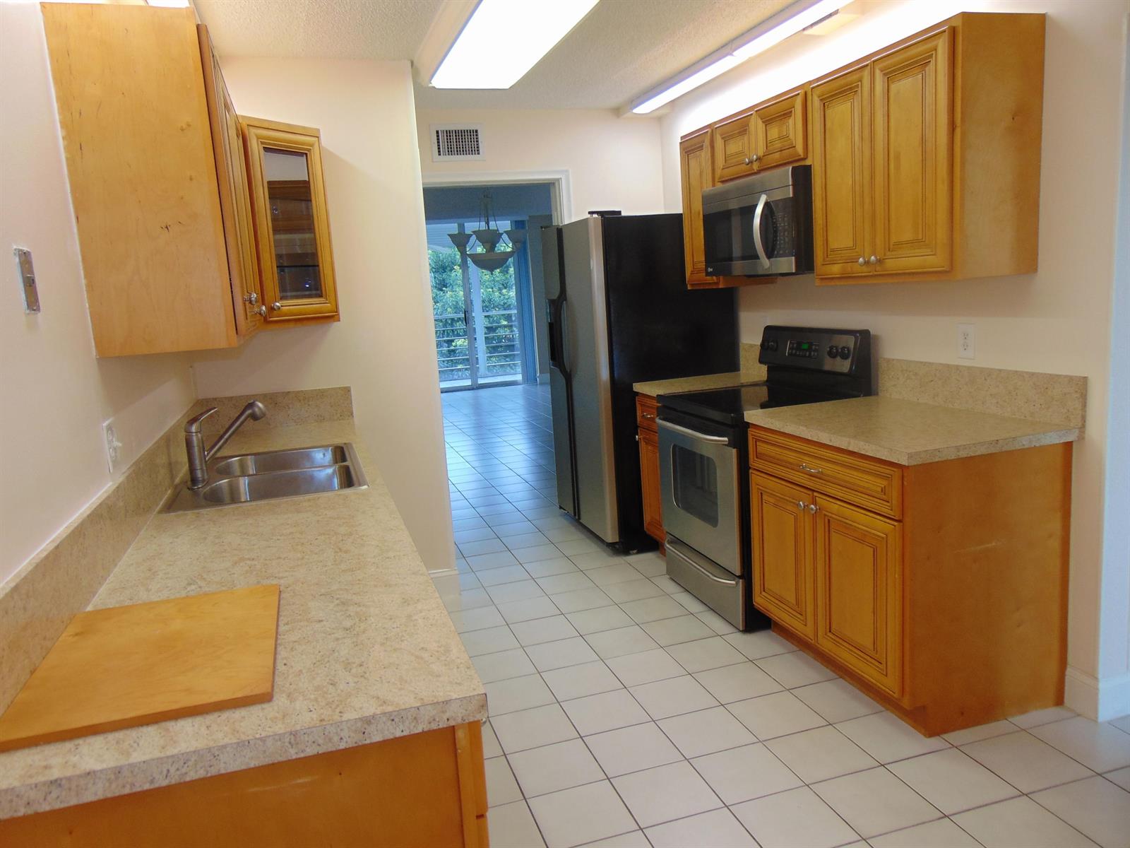 A kitchen with light wood cabinets, laminate countertops, stainless steel appliances, and white tile flooring — 3286 Arcara Way # 413, FL 33467, FL