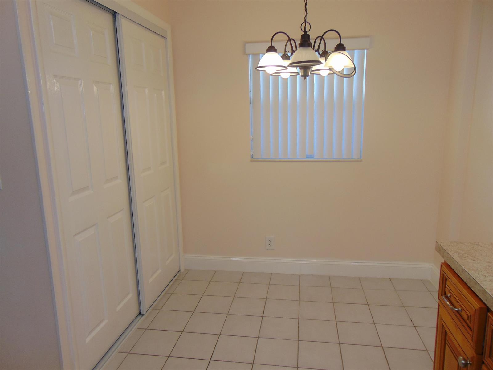 A room with light-colored walls, tiled flooring, a sliding closet, and a hanging light fixture — 3286 Arcara Way # 413, FL 33467, FL