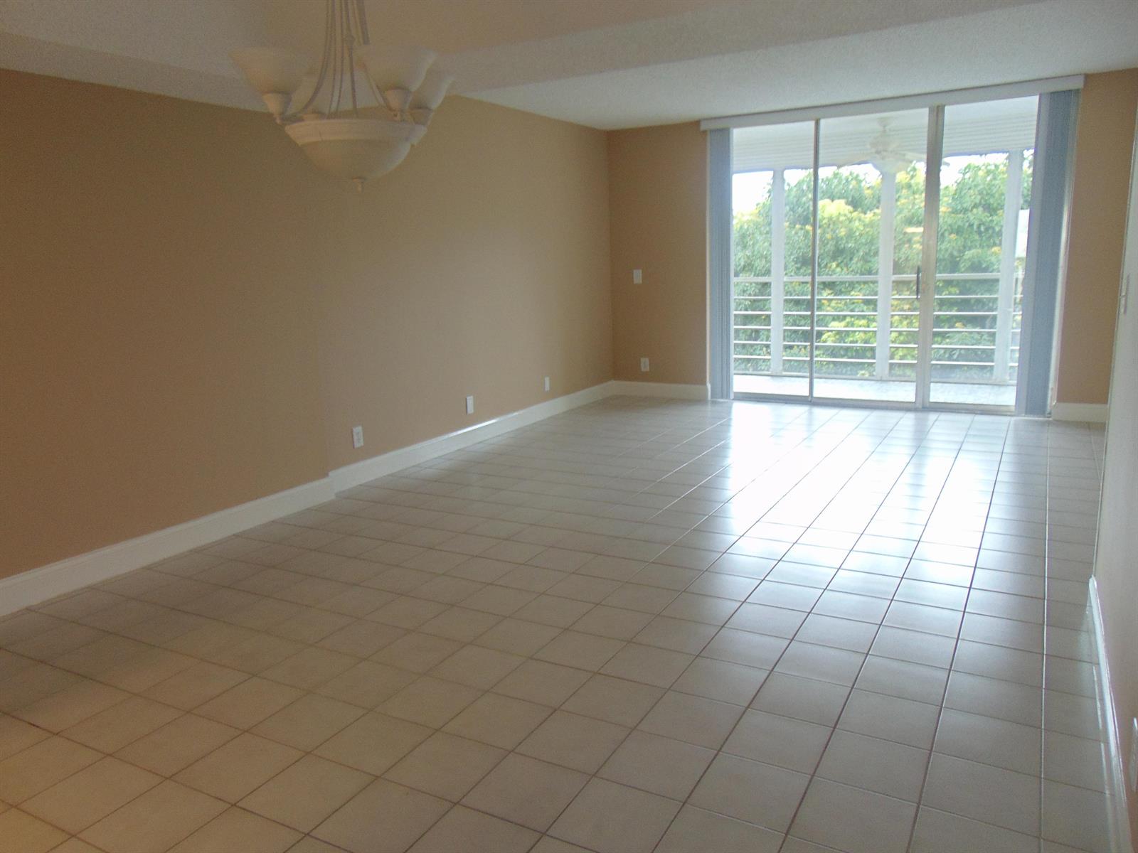 An empty room with beige walls, tile flooring, a chandelier, and a sliding glass door — 3286 Arcara Way # 413, FL 33467, FL