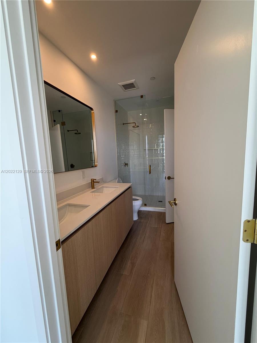 A bathroom features a double-sink vanity with light wood cabinets and a glass-enclosed shower — 90 NE 32nd ST # 1110, Miami FL 33145, MIAMI, FL