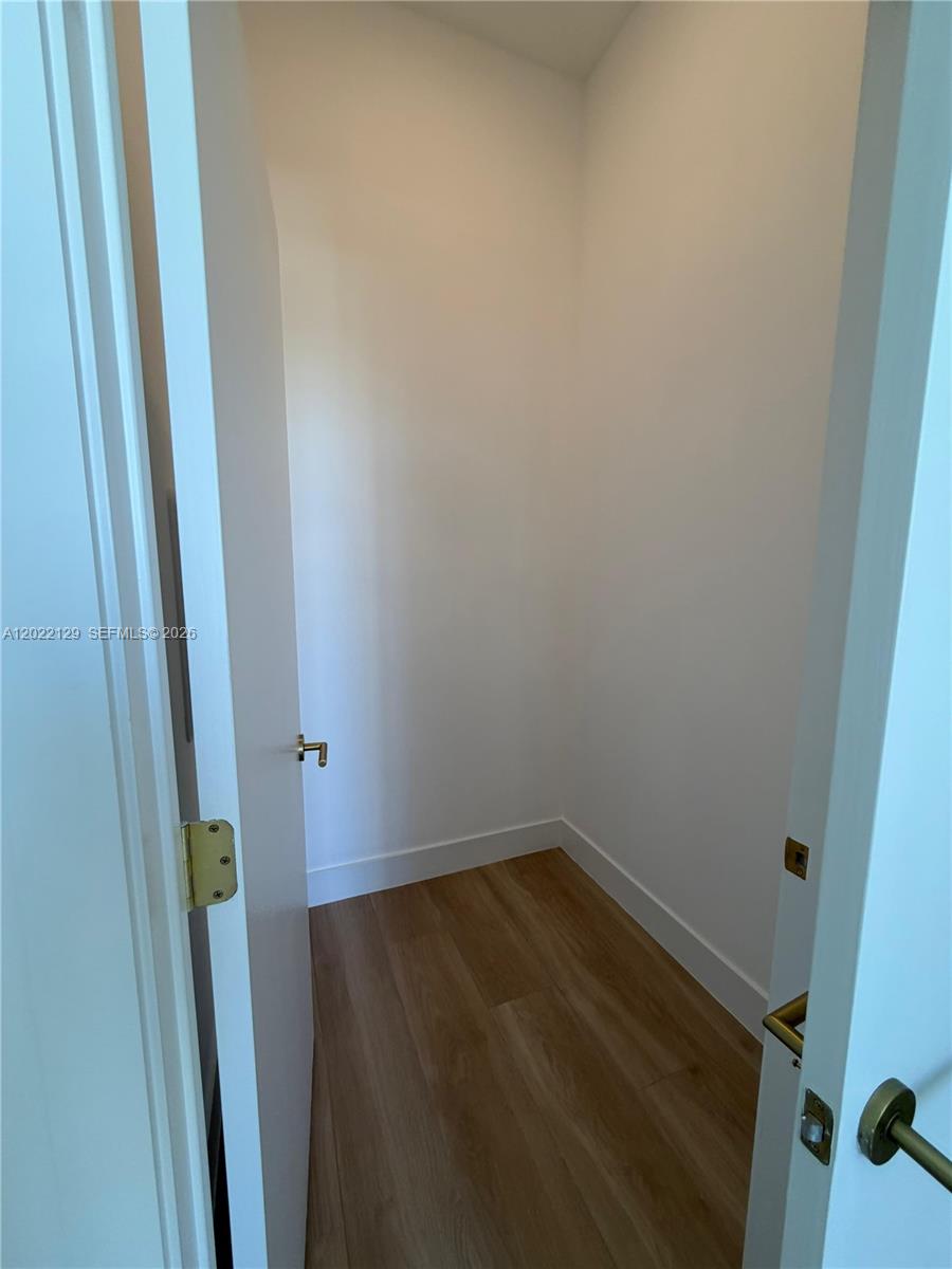 A small, empty closet features white walls and light-colored wood-look flooring — 90 NE 32nd ST # 1110, Miami FL 33145, MIAMI, FL