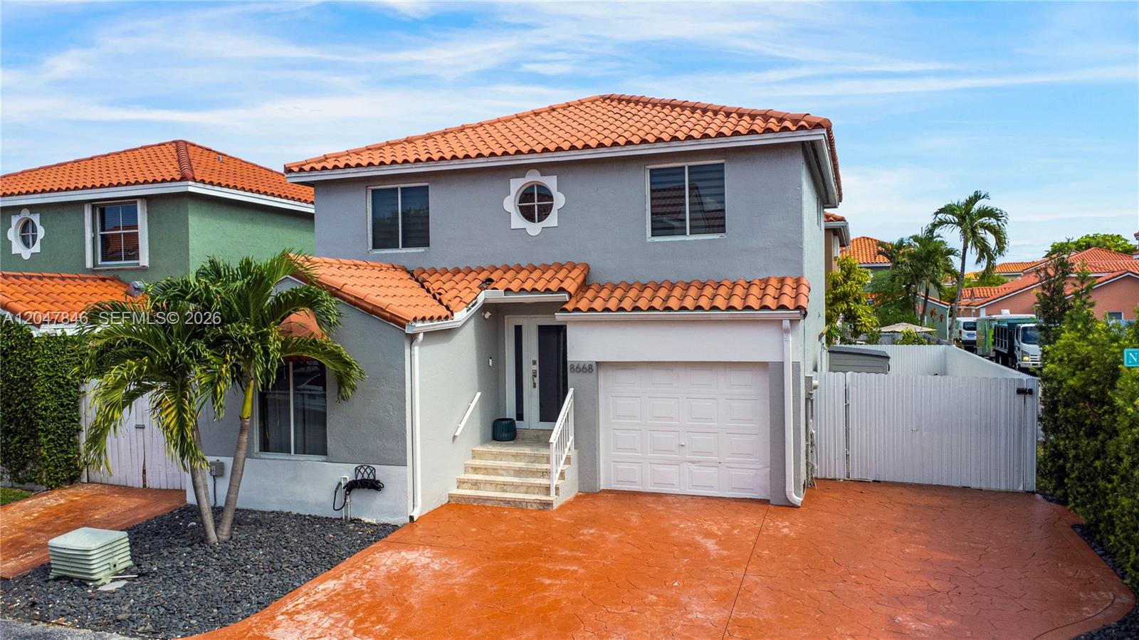 A two-story house with a terracotta tile roof, gray stucco walls, and a driveway — 8668 NW 2nd Ter, Miami FL 33126, MIAMI, FL
