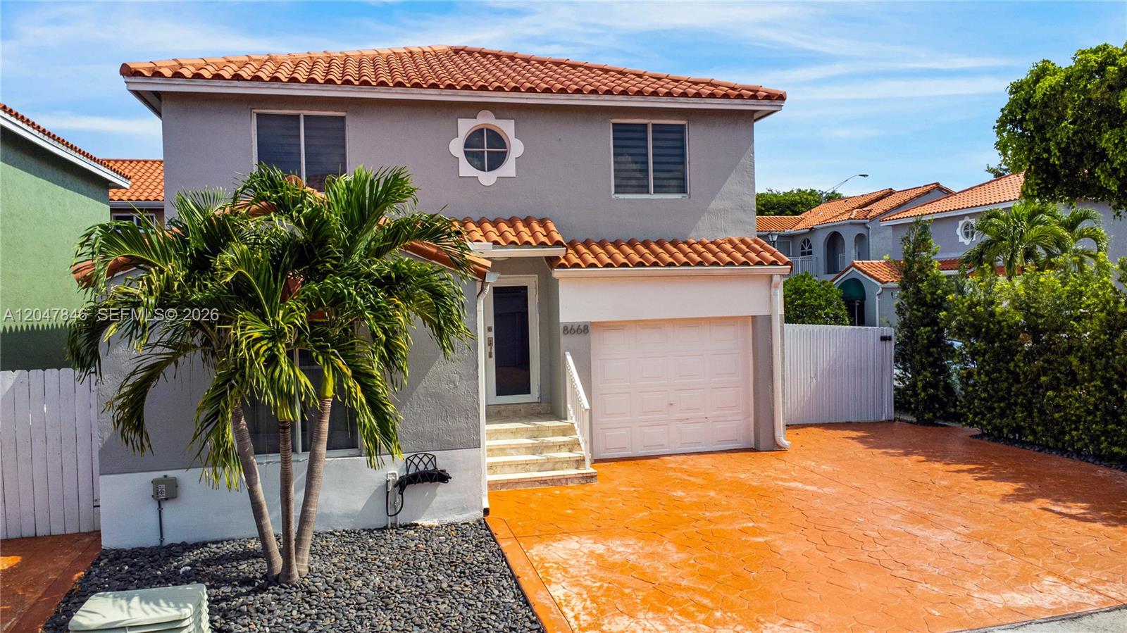 A two-story house with a tiled roof, gray stucco exterior, and an orange stamped concrete driveway — 8668 NW 2nd Ter, Miami FL 33126, MIAMI, FL