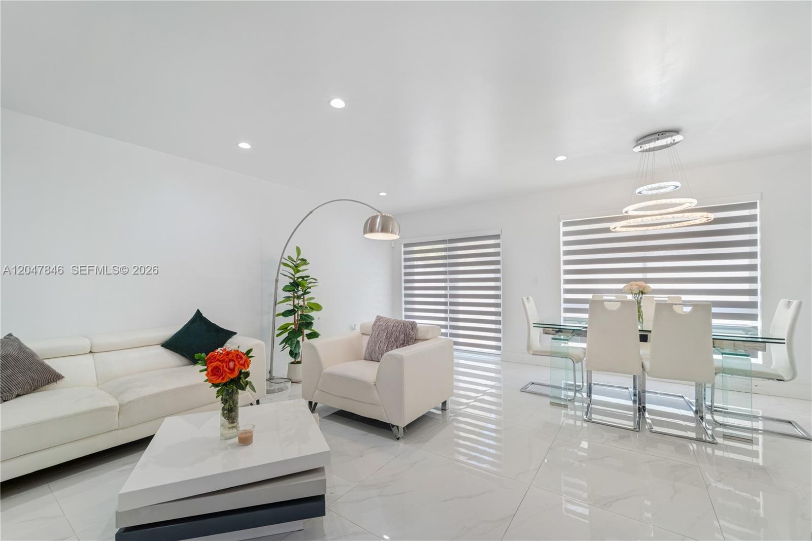 A bright, modern living and dining area features white furniture, tile floors, and pendant lighting — 8668 NW 2nd Ter, Miami FL 33126, MIAMI, FL