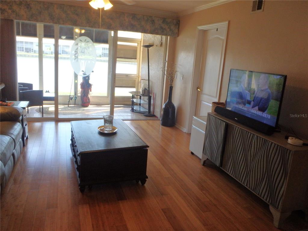 A living room features hardwood floors, a television on a cabinet, and sliding glass doors — 11644 SW EGRET CIRCLE UNIT 902, LAKE SUZY, FL