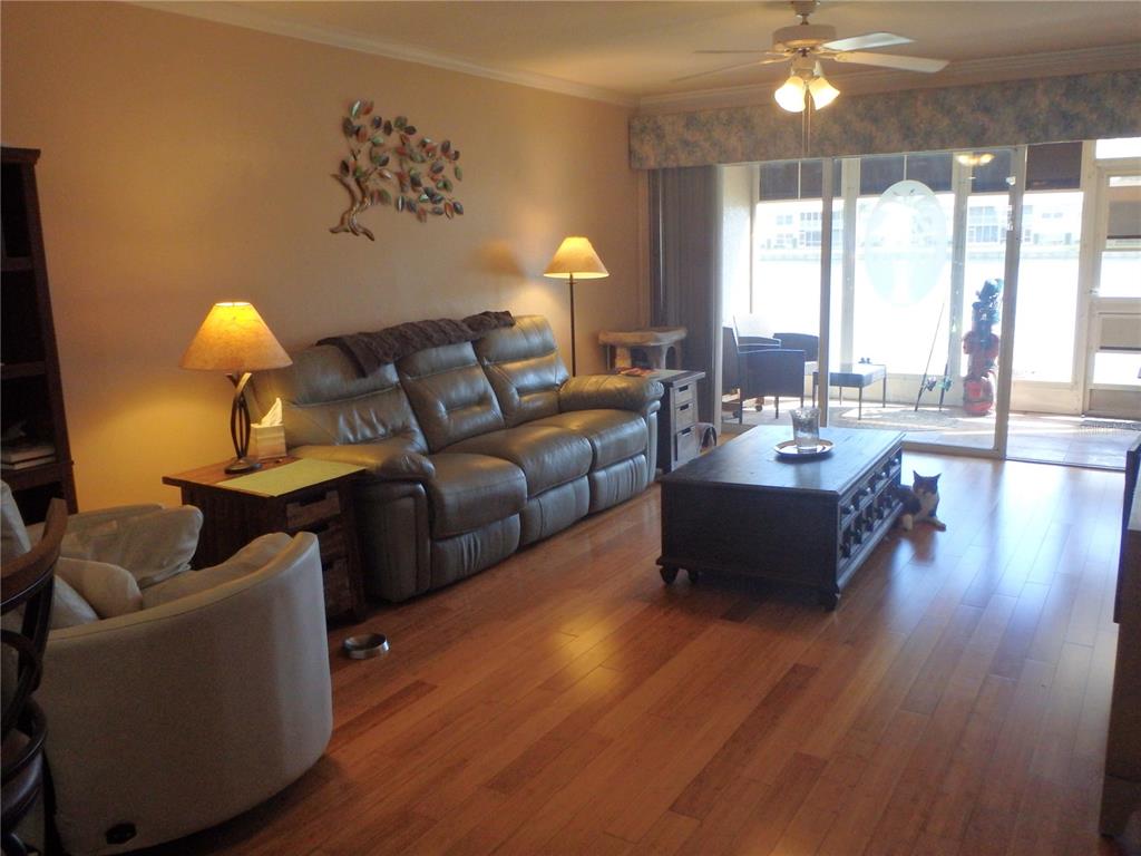 A living room features hardwood floors, a leather sofa, a coffee table, and a cat — 11644 SW EGRET CIRCLE UNIT 902, LAKE SUZY, FL