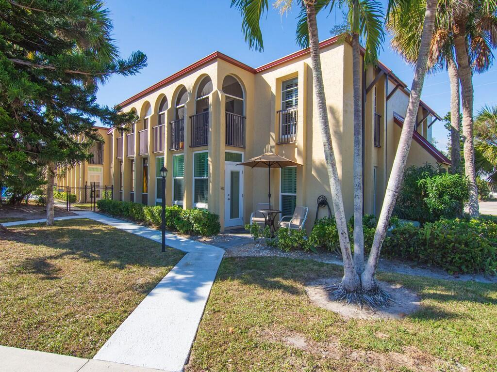 A two-story yellow stucco apartment building features arched balconies and a paved walkway — 4150 Highway A1A # 101, Vero Beach FL 32963, VERO BEACH, FL