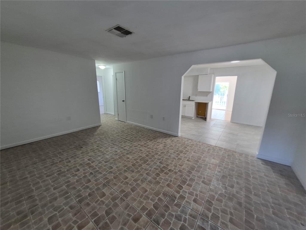 A living room with tiled flooring leads into an adjacent kitchen area — 9 MICHIGAN STREET, BEVERLY HILLS, FL