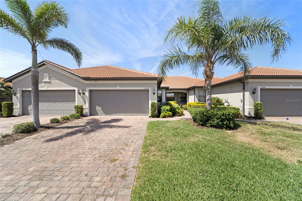 A single-story house with a tile roof, three garage doors, and two palm trees — 13908 ALAFAYA STREET, VENICE, FL