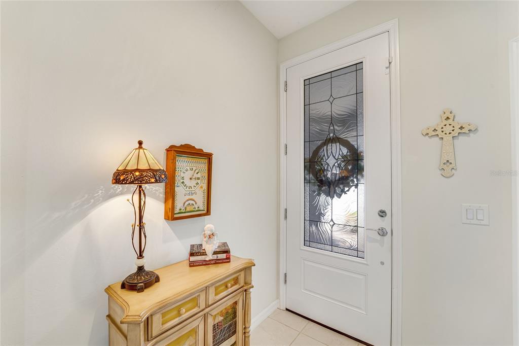 An entryway features a light-colored console table, a stained-glass lamp, and a white front door — 13908 ALAFAYA STREET, VENICE, FL