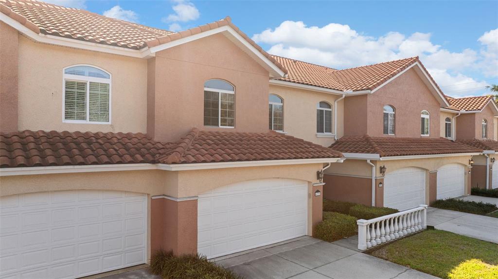A row of multi-story townhomes with stucco exteriors, tiled roofs, and attached garages — 6339 VISTA VERDE DRIVE E, GULFPORT, FL