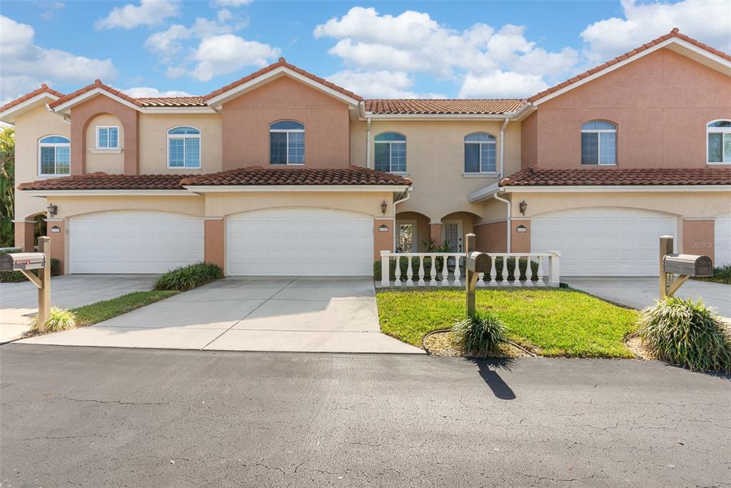 A multi-unit residential building with beige stucco walls, tile roofs, and attached garages — 6339 VISTA VERDE DRIVE E, GULFPORT, FL