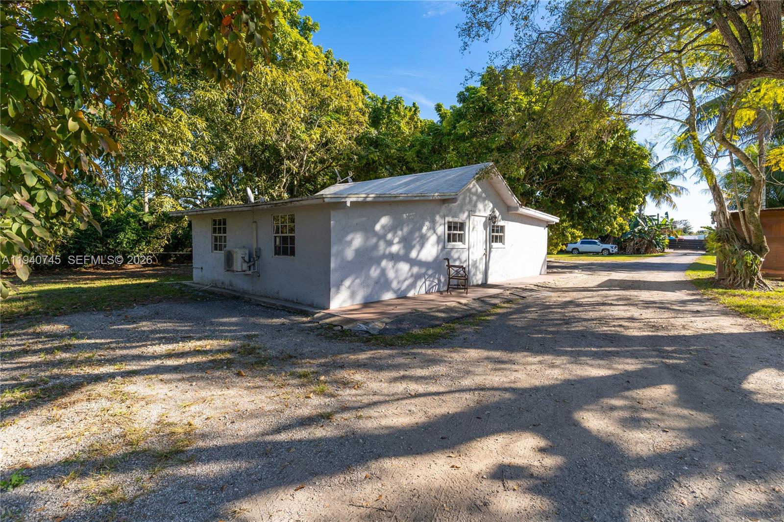 A small, white, single-story detached building sits on a gravel lot surrounded by trees — 19750 SW 136th St, Miami FL 33196, MIAMI, FL