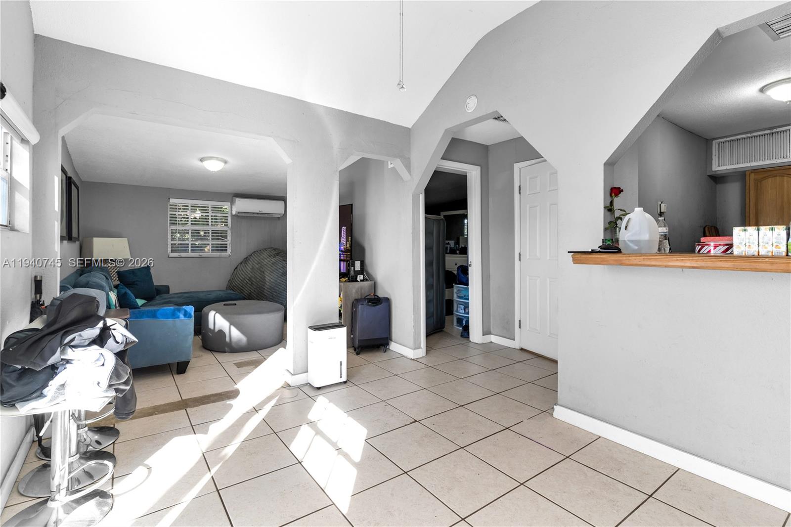 A living room with tiled floors, gray walls, and an arched opening to a kitchen — 19750 SW 136th St, Miami FL 33196, MIAMI, FL
