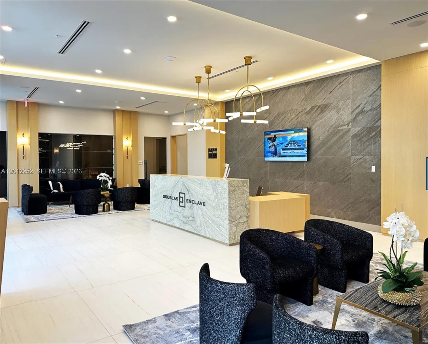 A modern lobby features a marble reception desk, dark textured armchairs, and gold pendant lighting — 61 NW 37th Ave # 11, Miami FL 33125, MIAMI, FL