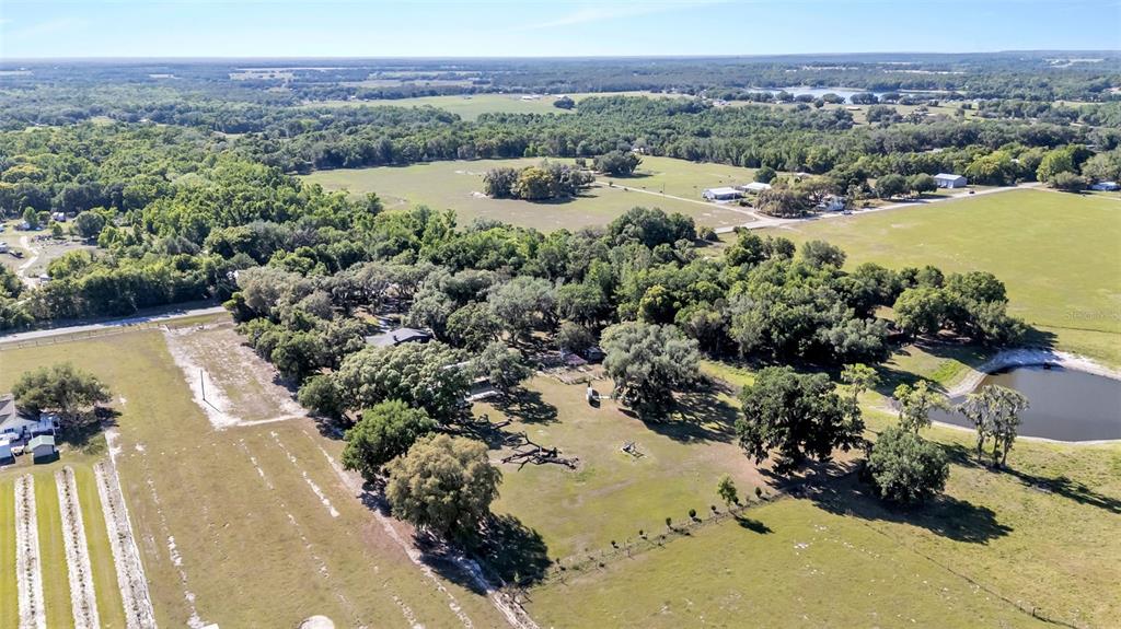 An aerial view shows a rural property with a house surrounded by trees and pastures — 15300 LAKE IOLA ROAD, DADE CITY, FL
