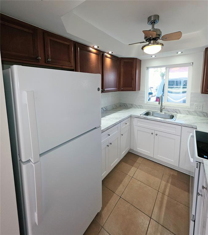 A kitchen features white lower cabinets, dark wood upper cabinets, and a white refrigerator — 4580 OVERLOOK DRIVE NE UNIT 190, ST PETERSBURG, FL