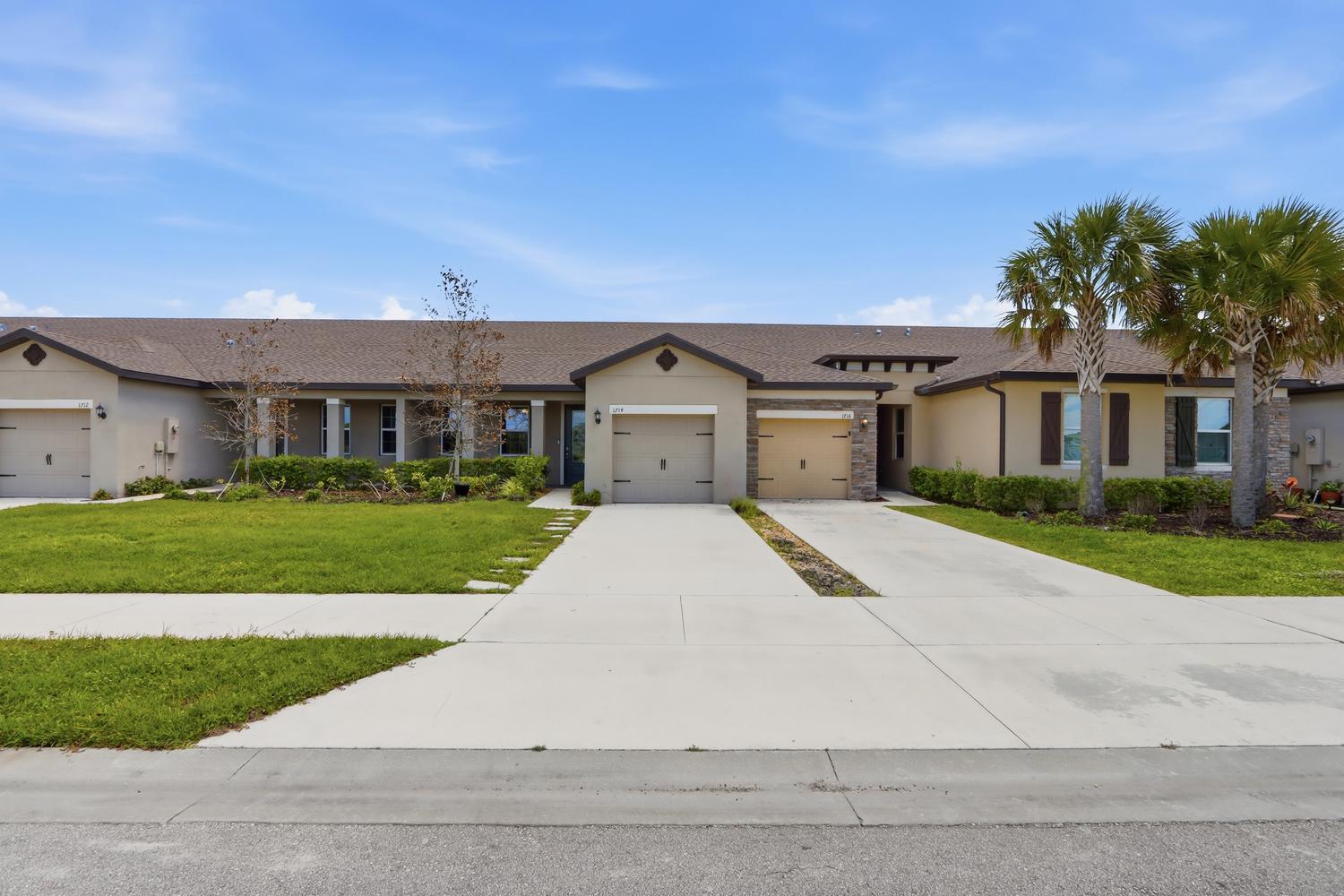 A single-story multi-unit residential building with beige stucco walls, brown shingle roofs, and concrete driveways — 1714 Celebration Drive, Fort Pierce FL 34947, FORT PIERCE, FL