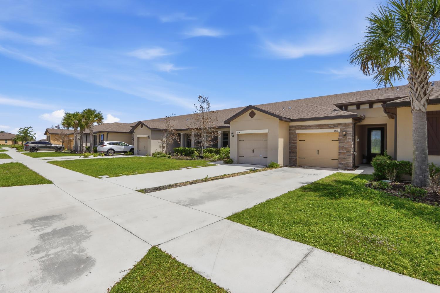 A row of single-story suburban houses with tan stucco exteriors and attached garages — 1714 Celebration Drive, Fort Pierce FL 34947, FORT PIERCE, FL