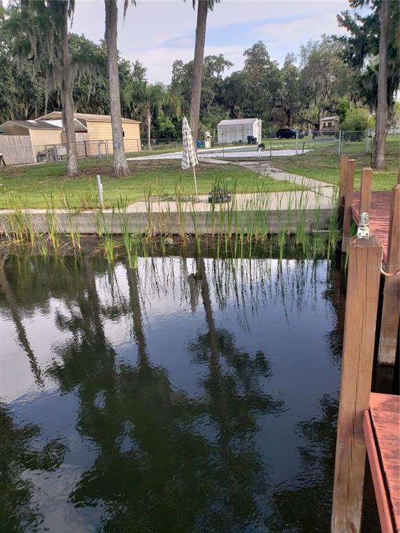 A view from a wooden dock looking toward a grassy yard with a small shed — 17101 ARROWHEAD BOULEVARD, WINTER GARDEN, FL