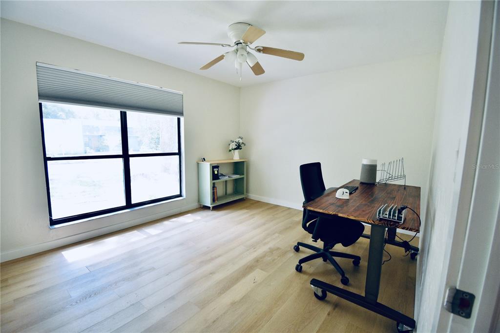 A home office features light wood flooring, a large window, a ceiling fan, and a desk — 2000 SW 11TH TERRACE, GAINESVILLE, FL
