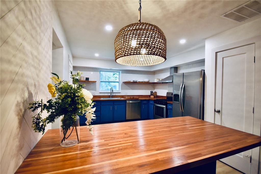 A kitchen features blue cabinets, a wooden island countertop, and a large woven pendant light — 2000 SW 11TH TERRACE, GAINESVILLE, FL