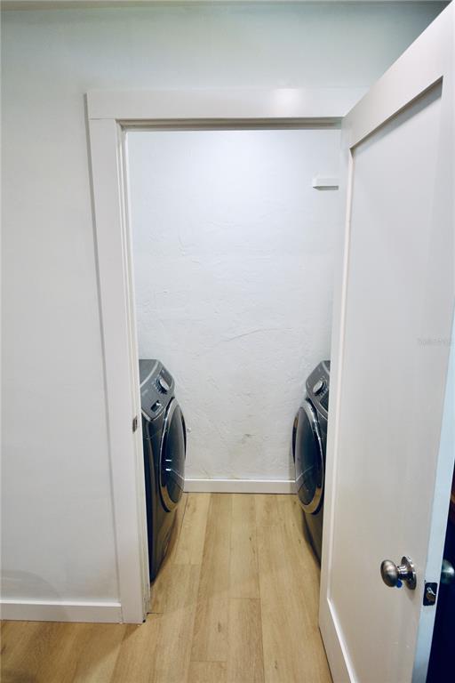 A laundry closet with a washer and dryer set on light wood-look flooring — 2000 SW 11TH TERRACE, GAINESVILLE, FL