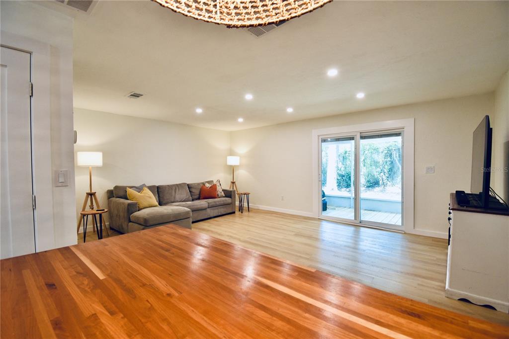 A living room features light wood flooring, a gray sectional sofa, and sliding glass doors — 2000 SW 11TH TERRACE, GAINESVILLE, FL