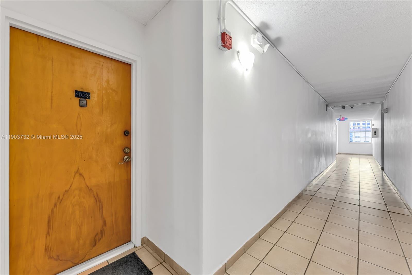 A wooden apartment door with number 402 opens into a long, tiled hallway — 3661 SW 9th Ter # 402, Miami FL 33135, MIAMI, FL