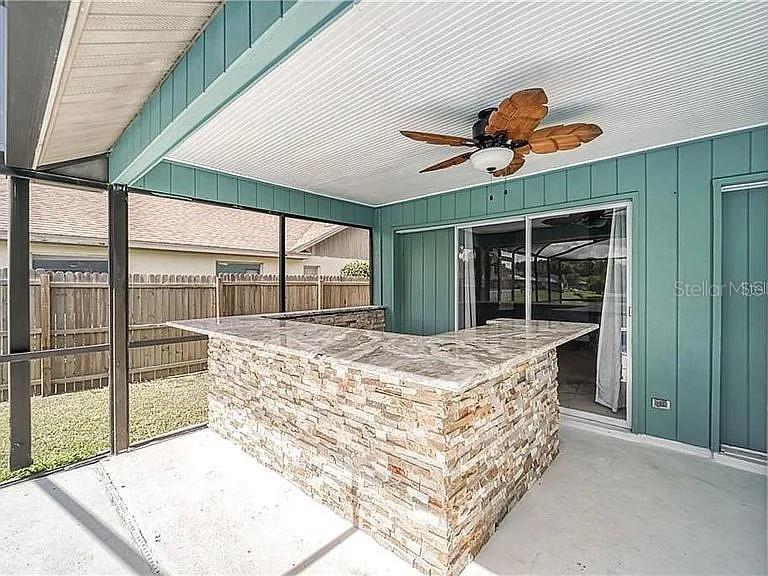 A covered patio features a stone-faced bar with a granite countertop and a ceiling fan — 4314 ELLENVILLE PLACE, VALRICO, FL