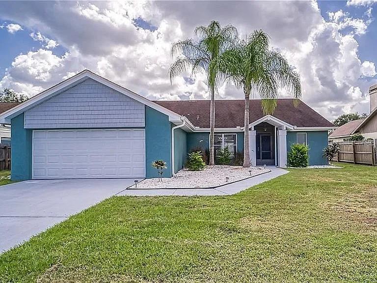 A teal single-story house features a two-car garage, palm trees, and a gravel front yard — 4314 ELLENVILLE PLACE, VALRICO, FL