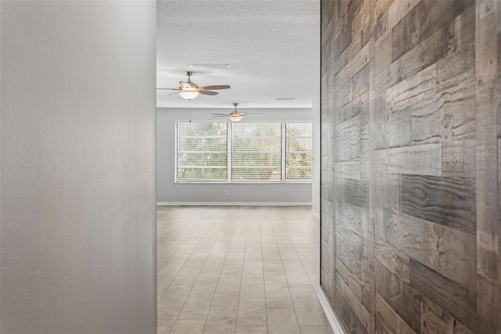 A view through a doorway into a room with tile flooring and two ceiling fans — 5501 80TH STREET N UNIT 402, ST PETERSBURG, FL
