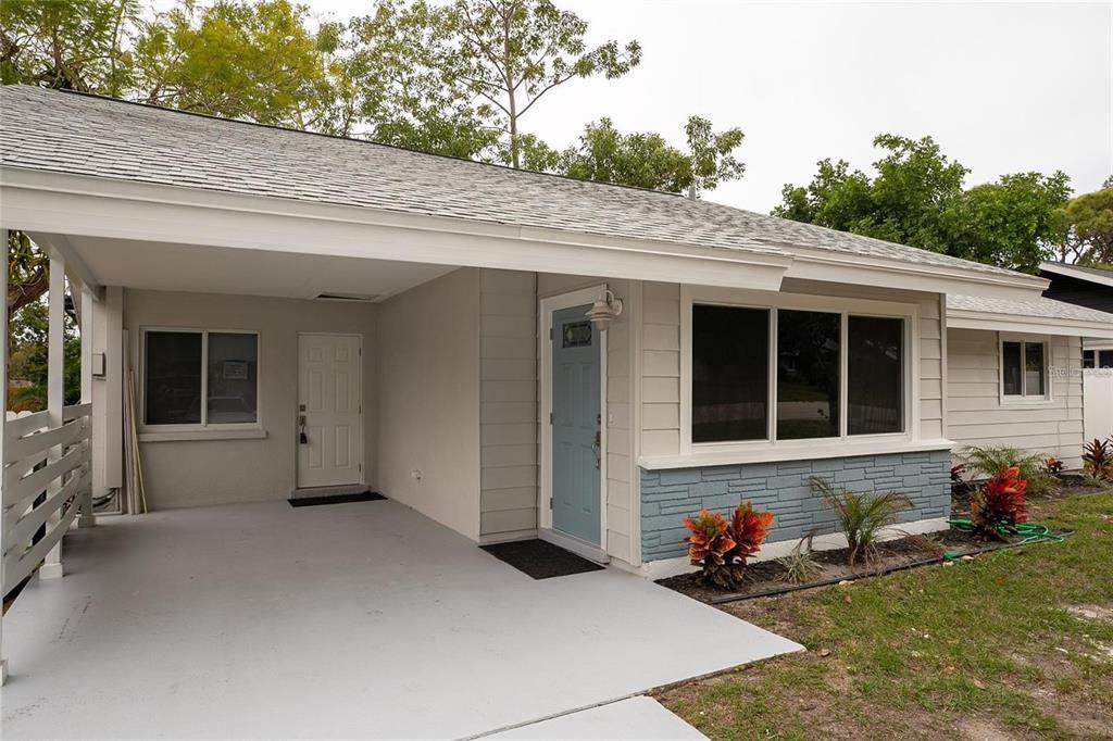 A single-story house exterior featuring a light blue front door and a covered carport — 2722 NANCY STREET, SARASOTA, FL