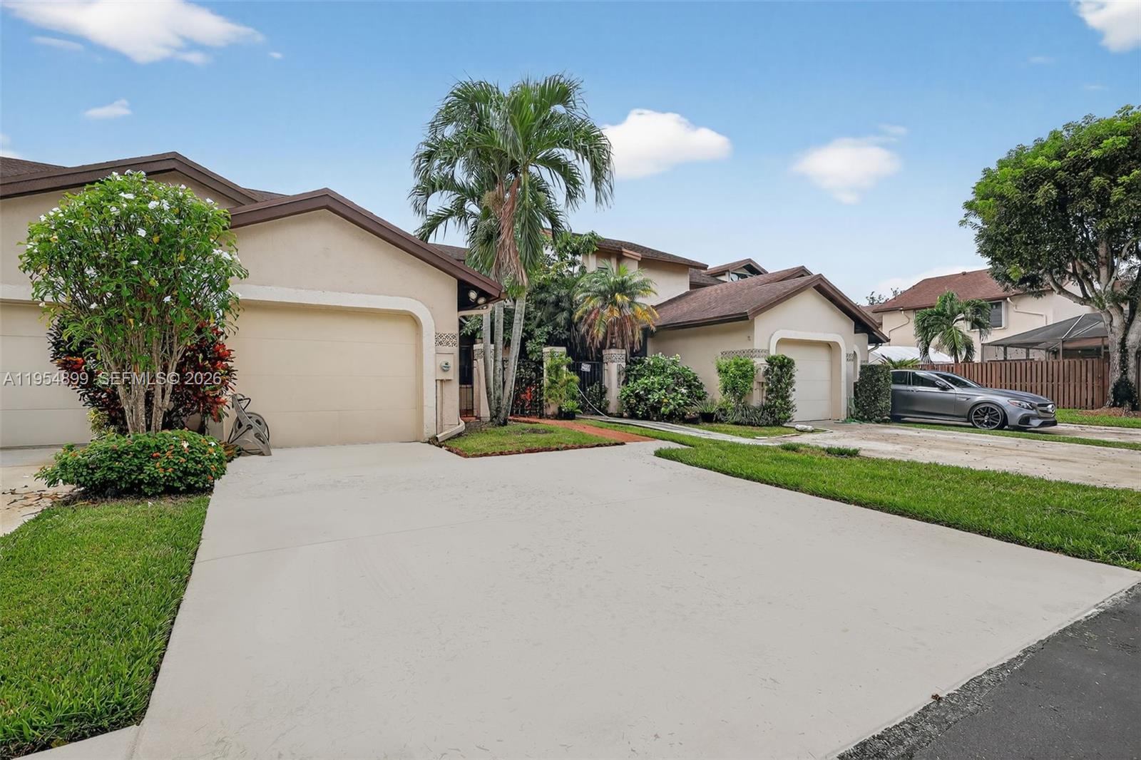 A beige house with a two-car garage, a concrete driveway, and palm trees — 13702 SW 101st Ter, Miami FL 33186, MIAMI, FL