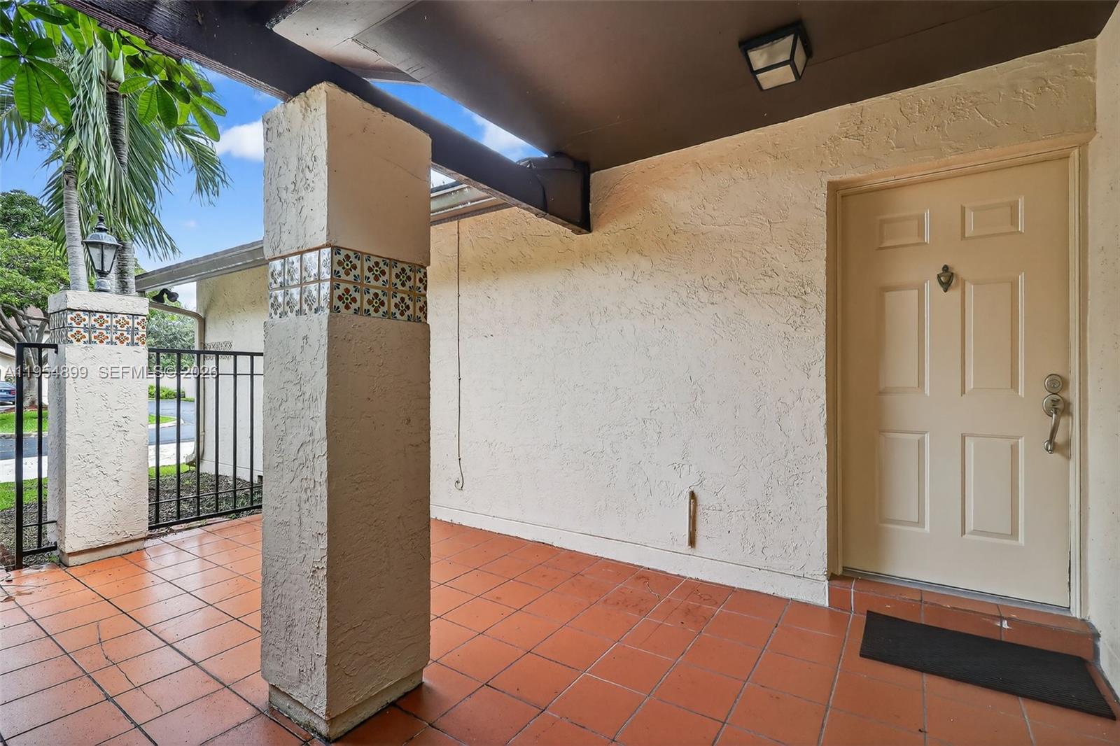 A covered patio features terracotta tile flooring, stucco walls, and decorative tiled columns — 13702 SW 101st Ter, Miami FL 33186, MIAMI, FL