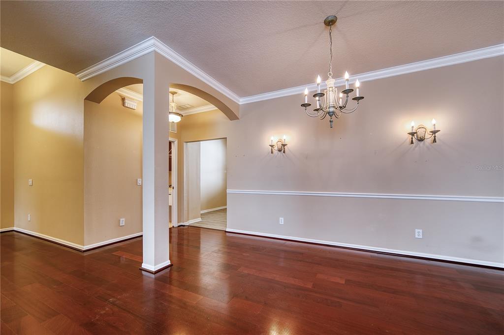 A dining room with hardwood floors, a chandelier, wall sconces, and crown molding — 4252 MACKAY FALLS TERRACE, SARASOTA, FL