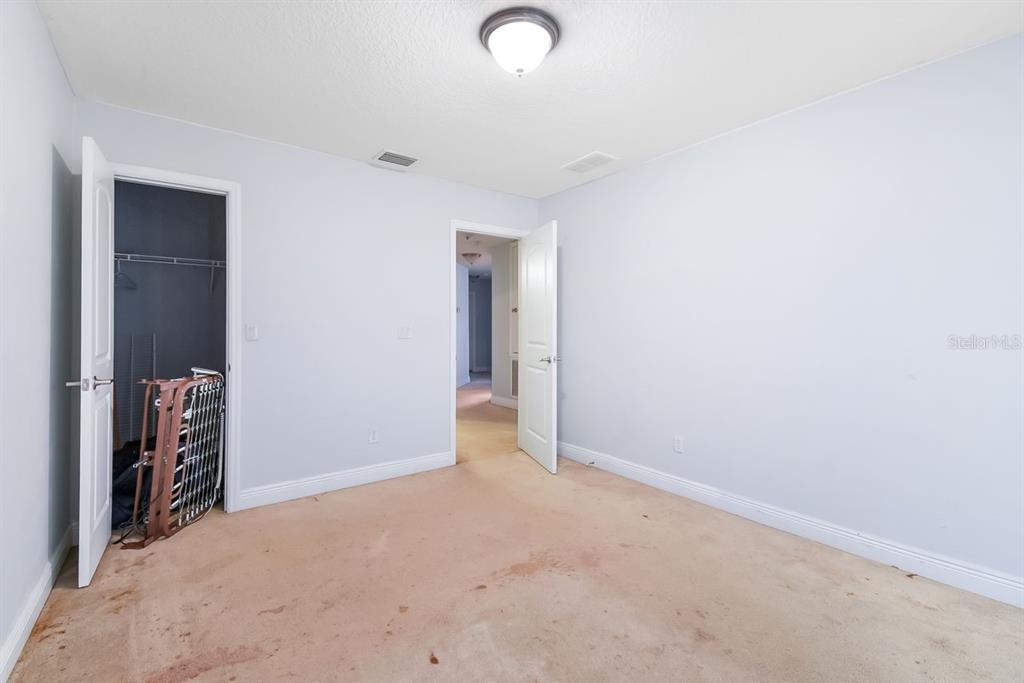 An empty bedroom features light blue walls, a beige carpet, and two open doorways — 46 RIDDLE DRIVE, PALM COAST, FL