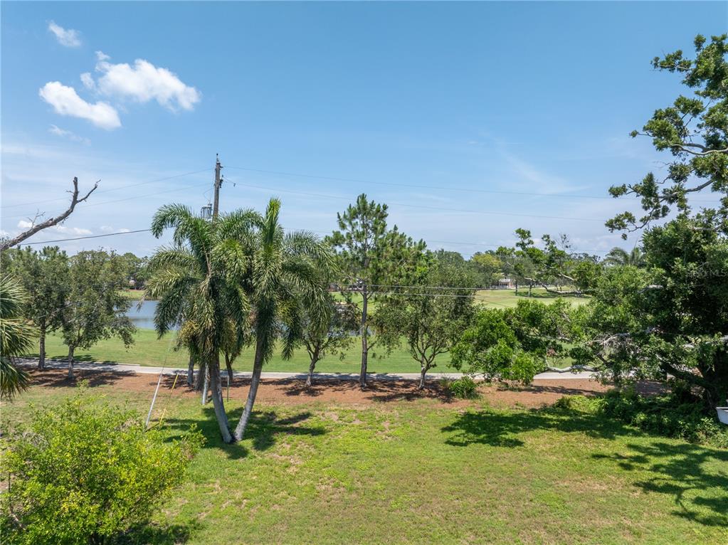 A grassy backyard overlooks a golf course with a pond and several trees — 167 ALMEDO WAY NE, ST PETERSBURG, FL